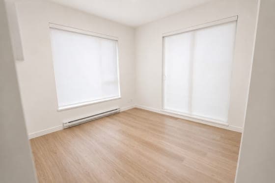 An empty bedroom with a sliding door and a window on the left wall